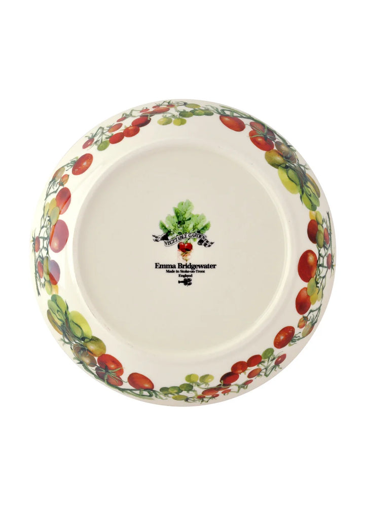 A round ceramic plate from Emma Bridgewater, shown from a top-down view. The plate features a white base decorated with a border of red and green tomatoes on the rim, and the brand&