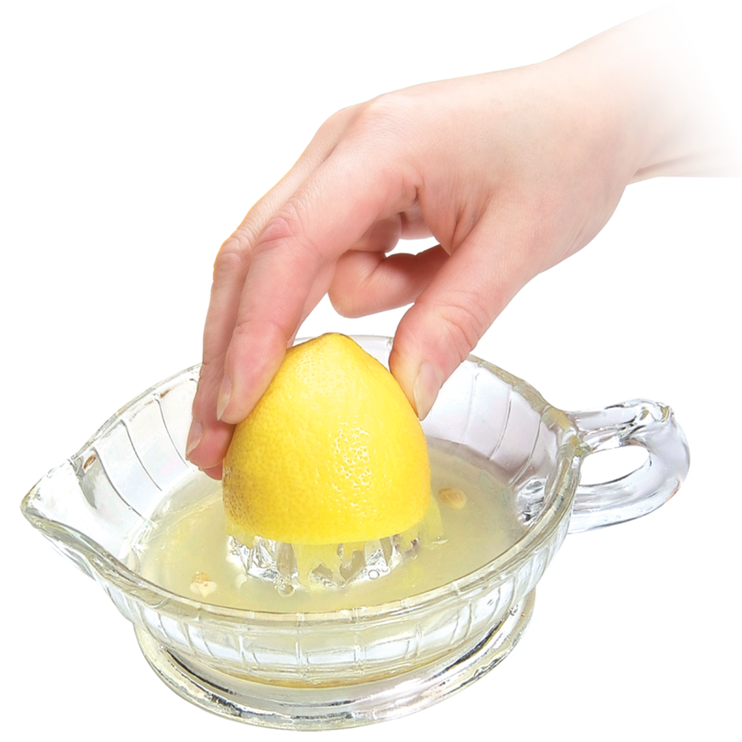 Hand using a glass lemon squeezer to extract juice from a lemon on a white background