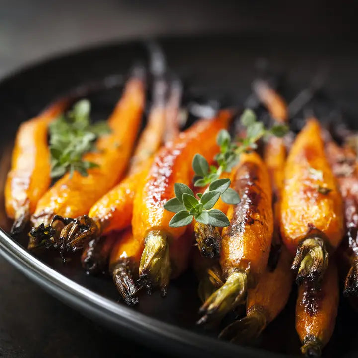 Roasted carrots with thyme on a dark plate