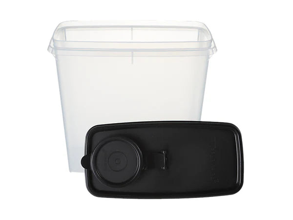 A clear plastic storage container with a transparent lid shown behind a black rectangular lid or cap with a circular component, photographed on a white background.