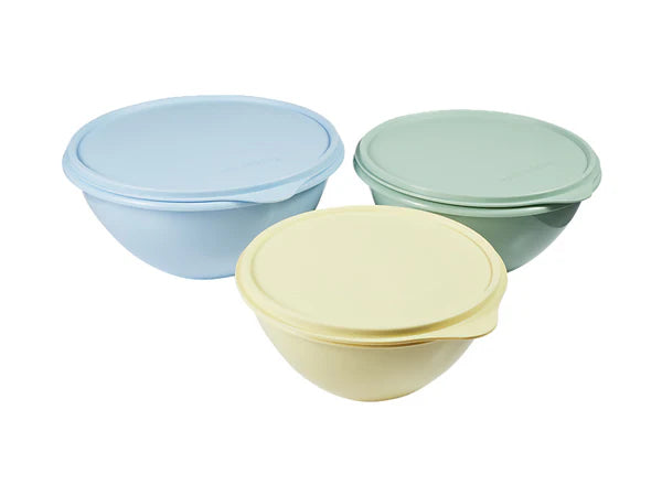 Three pastel-colored bowls with lids on a white background