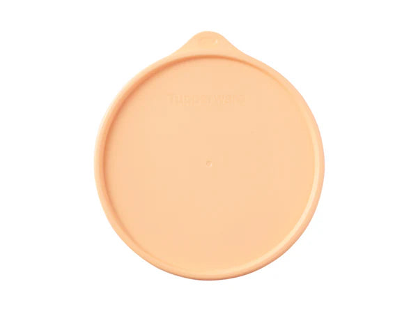 A peach-colored circular plastic lid with a small tab at the top, shown on a plain white background.