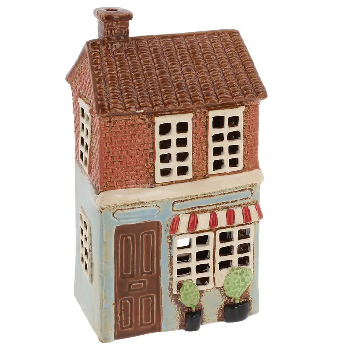 Small ceramic tealight holder of a two-story building with a brown roof and blue facade.