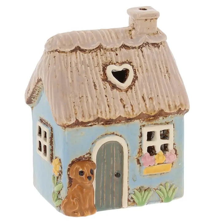 Small ceramic house tealight holder with a thatched roof and heart-shaped window on a white background