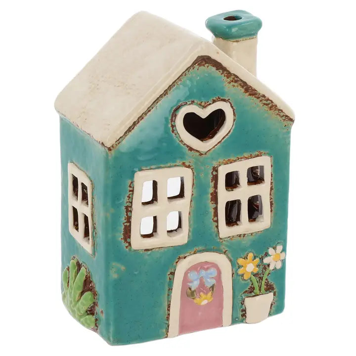 Ceramic house-shaped tealight holder with a heart window and pink door on a white background