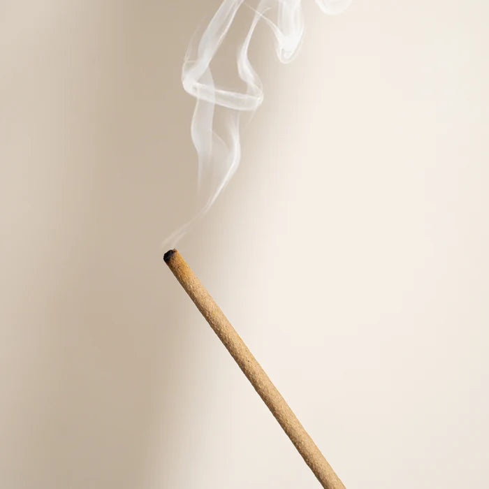 Incense stick with smoke against a beige background