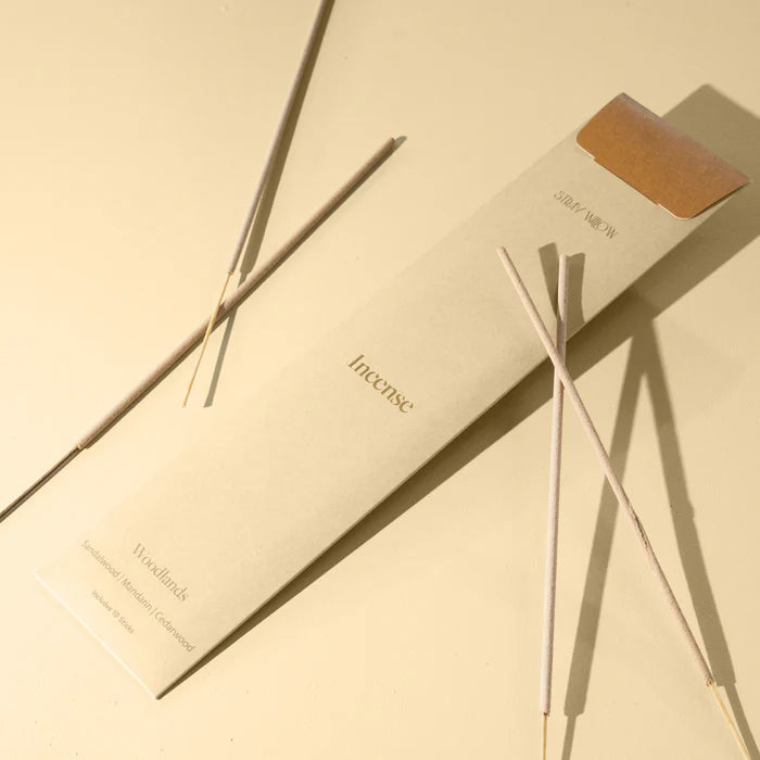 A packet of incense sticks on a light yellow background with incense sticks laying on the packaging