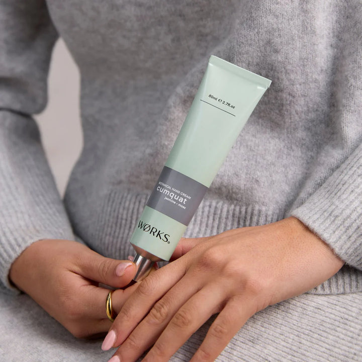 Person applying a tube ofcumquat Works hand cream to their hand.