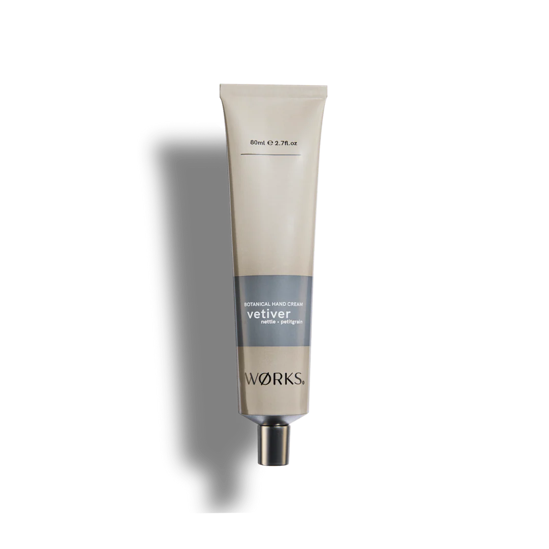 A beige tube of Works vetiver hand cream on a white background