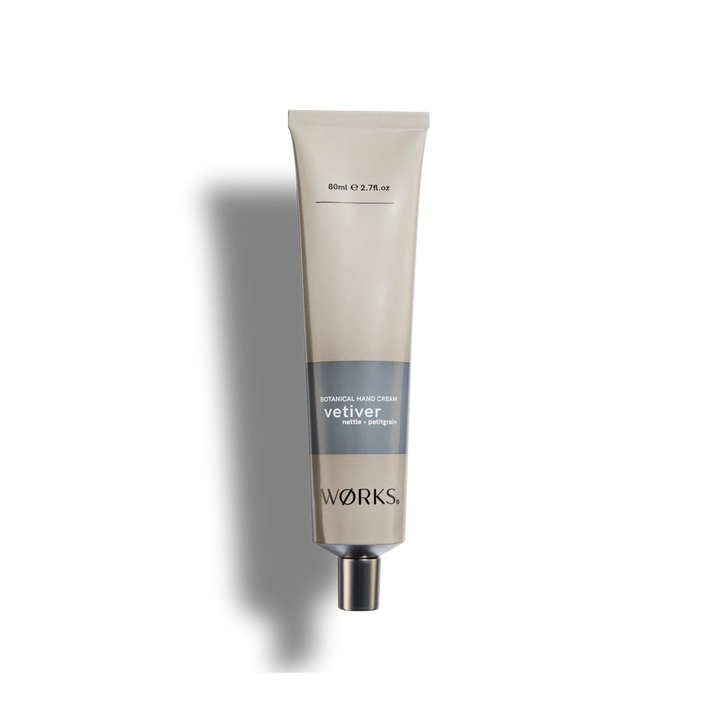 A beige tube of Works vetiver hand cream on a white background