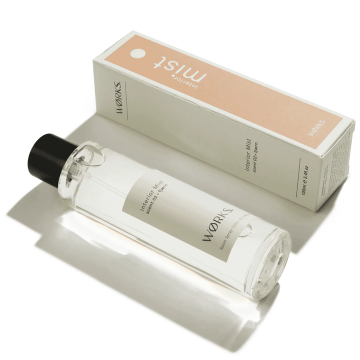 Clear bottle with black cap and beige label next to a beige box with &