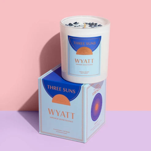 Three Suns Wyatt candle and box on a purple shelf &amp; pale pink background