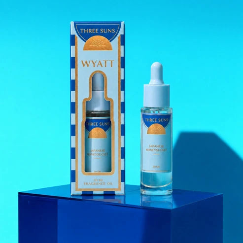 A bottle of Three Suns Wyatt fragrance oil refill on a blue stand on a blue background