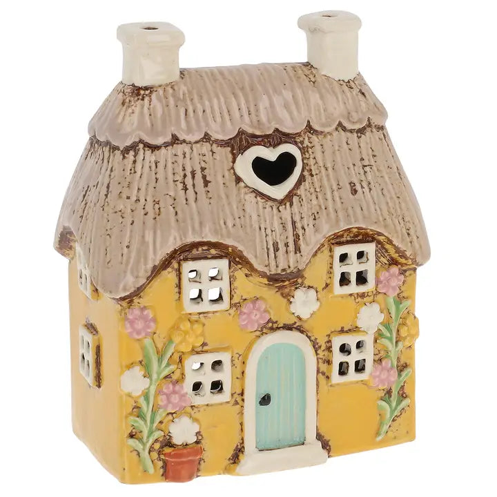 Decorative miniature house tealight holder with a thatched roof and heart-shaped window on a white background