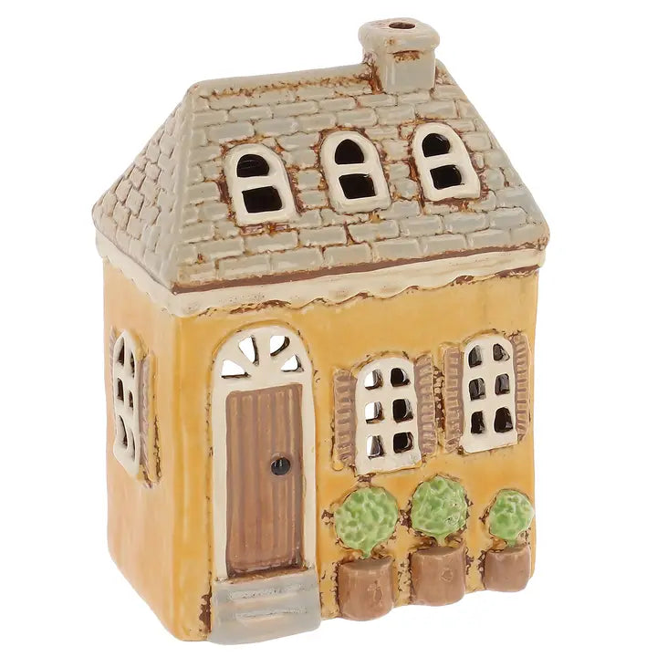 A yellow ceramic house tealight holder on a white background